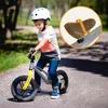 A young boy is riding a balance bike on a paved path outdoors. Produktbild-Vorschau
