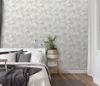 A bedroom scene with a bed, pillows, and a plant, showcasing the wallpaper. Produktbild-Vorschau