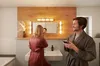 A couple in a bathroom, with the woman applying makeup and the man looking at his phone. Podgląd zdjęcia produktu