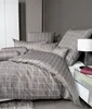 A neatly made bed with grey and white checkered bedding, including a duvet and pillows, in a modern bedroom setting. Produktbild-Vorschau