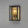 A wall-mounted light fixture with a glass enclosure and a brass-colored interior, featuring an Edison-style light bulb. Produktbild-Vorschau