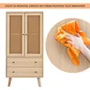 A cabinet with cane doors and drawers is shown next to a hand wiping a wooden surface with an orange cloth. Produktbild-Vorschau