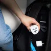 A person is placing a white travel adapter into a black backpack. Produktbild-Vorschau