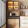 A tall, narrow cabinet with glass doors and internal LED lighting, designed for storing bottles and glassware, placed in a room setting next to a window and kitchen counter. Náhled obrázku produktu