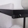 Close-up of a black side table next to a light gray upholstered chair. Podgląd zdjęcia produktu