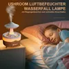 A child sleeping peacefully in bed next to a humidifier that is emitting mist and has a soft light. Produktbild-Vorschau