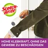A person is using a lint roller on their jacket. Produktbild-Vorschau
