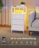 A white nightstand with drawers and integrated LED lighting, placed next to a sofa. Produktbild-Vorschau