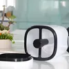 A white and black humidifier is shown on a table with plants in the background. Voir les images du produit