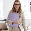 A woman in a business suit holds a lavender laptop sleeve in an office setting. Náhled obrázku produktu