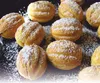 A close-up shot of several small, round pastries dusted with powdered sugar. Produktbild-Vorschau