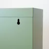 A close-up view of the corner of a green metal cabinet with a keyhole-shaped mounting hole. Anteprima dell’immagine prodotto