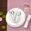 A table setting with plates, cutlery, a wine glass, and floral decorations on a pink placemat. Anteprima dell’immagine prodotto