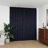 A dark anthracite curtain hangs across a white wall, with a potted plant to the left and a wooden dresser to the right. Anteprima dell’immagine prodotto