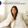 A woman is sitting in bed, wrapped in a white blanket. Produktbild-Vorschau