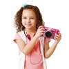 A young girl is holding a pink digital camera and smiling. Produktbild-Vorschau