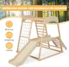 A wooden indoor playground with a slide, climbing net, and ladder, set against a backdrop of trees and sunlight. Produktbild-Vorschau