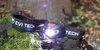 A headlamp is placed on a mossy log in a forest setting. Náhled obrázku produktu