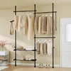 A black metal garment rack with shelves, holding various clothing items and accessories, set against a cream-colored wall. Podgląd zdjęcia produktu
