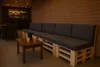 A lounge area with a pallet sofa and a coffee table in front of a brick wall. Anteprima dell’immagine prodotto