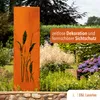 A rusty metal garden screen with a pampas grass design stands in a garden setting, surrounded by plants and flowers. Produktbild-Vorschau