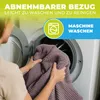 A person is holding a folded blanket in front of an open washing machine. Produktbild-Vorschau