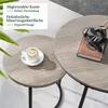 Two round coffee tables with a wood-grain finish and black metal legs, one with a cup of coffee and the other with a book and decorative object. Produktbild-Vorschau