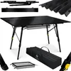 A black foldable camping table with its accessories, including a carrying bag and a mesh basket, displayed on a white background. Produktbild-Vorschau