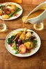 Gravy being poured over a plate of roasted chicken and vegetables. Anteprima dell’immagine prodotto