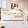 A white daybed with integrated LED lighting, USB port, and storage, set in a bedroom with framed pictures on the wall. Produktbild-Vorschau