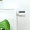 A white smart thermostat head attached to a white radiator, with a large green leaf in the foreground. Náhľad obrázku produktu