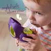 A young child is drinking from a purple and green sippy cup with a straw. Náhled obrázku produktu