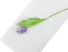 A single purple tulip with a green stem and leaf lies diagonally on a white fabric. Produktbild-Vorschau