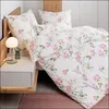A close-up view of a bed with floral patterned bedding, a bedside table with a lamp, and a rug. Produktbild-Vorschau