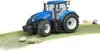 A blue New Holland T7.315 tractor toy is shown on a green and brown textured surface with rocks. Voir les images du produit