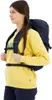 A young woman wearing a yellow sweatshirt and dark pants is shown from the side, wearing a dark blue backpack. Náhled obrázku produktu