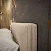 A close-up view of a bed's upholstered headboard and a pillow. Produktbild-Vorschau