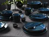 A table setting with blue and black stoneware plates, bowls, and mugs. Produktbild-Vorschau