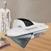 A white and black steam iron is shown on a wooden table, with a mannequin dressed in a patterned outfit in the background. Produktbild-Vorschau