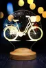 A 3D LED lamp shaped like a bicycle, displayed on a wooden base against a dark, bokeh background. Produktbild-Vorschau