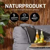 A close-up of a gray sofa with two bottles of drinks and a bowl of fruit on a wooden tray. Produktbild-Vorschau
