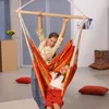 Two young girls are enjoying a colorful hammock chair indoors. Produktbild-Vorschau