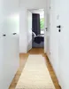 A hallway with white walls and doors, leading to a bedroom with dark curtains. Voir les images du produit