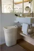 A bathroom scene with a laundry basket next to a sink. Anteprima dell’immagine prodotto