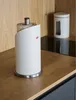 A white Wesco paper towel holder sits on a wooden countertop next to a white storage container. Produktbild-Vorschau