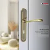 A close-up of a bronze door handle on a white door, with a blurred background of a room interior. Produktbild-Vorschau