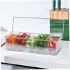 A clear plastic container with five compartments filled with chopped vegetables and tomatoes, resting on a white countertop with ice cubes below. Produktbild-Vorschau