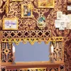 A miniature diorama of a bookshelf corner with decorative elements and a mirror. Voir les images du produit