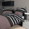 A neatly made bed with striped bedding and pillows in a modern bedroom setting. Produktbild-Vorschau