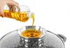 A hand is pouring cooking oil from a plastic bottle into a small metal bowl. Náhled obrázku produktu